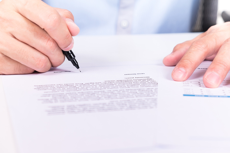 businessman's hand signing a document on desk